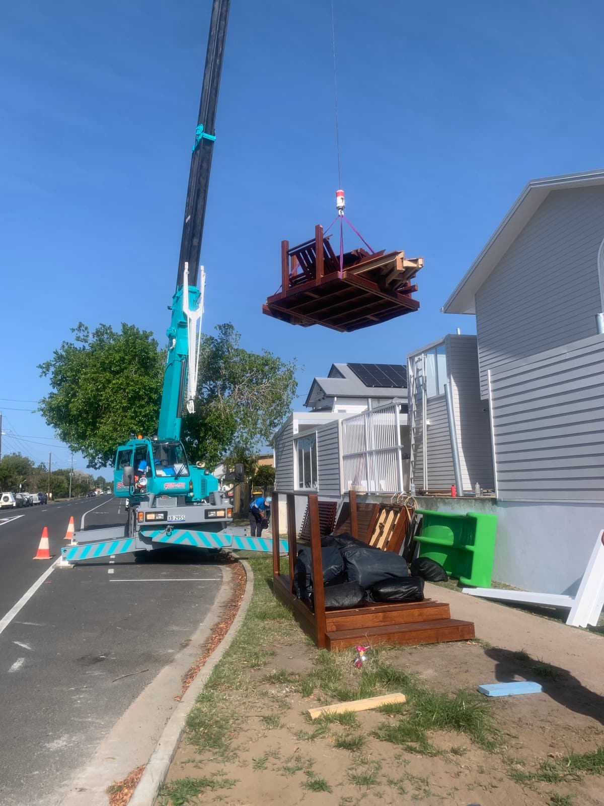 Crane on the street lifting a timber deck section over a building in East Mackay